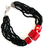 Black beaded multi strings forming fashion bracelet with rounded red beads in middle