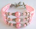 Silver stripped triple pink color beaded strings fashion bracelet holding 3 pinky, flower silver beads and large silver capped pink color beads at center