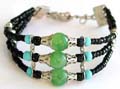 Fashion Tibetan bracelet with triple black beaded strings holding 3 mini blue, black and large silver capped green beads at center