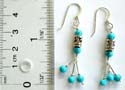 Sterling silver fish hook earring with 2 rounded turquoise beads and a Tibetan style spinning bead at center holding 3 beaded strips on bottom