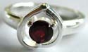 Sterling silver rign with a rounded red garnet stone embedded carved-out heart shape pattern decor at center