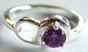 Sterling silver ring with carved-out double knot pattern holding a rounded amethyst stone at center