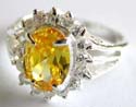 Multi mini clear cz forming flower pattern decor sterling silver ring holding an oval shape yellow cz stone in middle