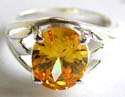 Sterling silver ring with carved-out leaf pattern holding an oval shape yellow cz stone in middle 