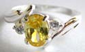 Sterling silver ring with carved-out line pattern holding an oval shape yellow cz stone at center and a mini clear cz on each side