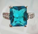 Greenish blue cz ring with multi mini clear cz on both sides, plated with rhodium and brass base