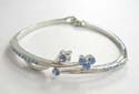 Fashion bangle bracelet with mini light blue cz embedded on both sides and 5 rounded light blue cz embedded in flower pattern decor at center