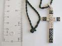 Fashion necklace with black twisted cord string holding a cross mental pendant with black enamel at edges 