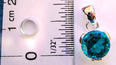 Sterling silver pendant holding a rounded dark blue cubic zircon ia at center     
