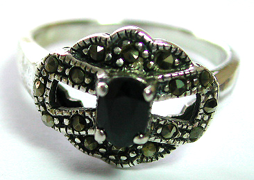 Sterling silver ring with carved-out flower pattern holding an elliptical shape red garnet stone