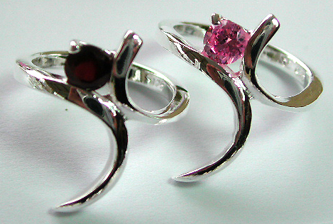 Sterling silver ring with curvy stand central design holding a rounded pinkish cz / red garnet stone in middle 