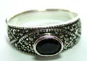 Sterling silver ring with multi macasite stones embedded geometrical pattern holding an elliptical shape black onyx stone in middle