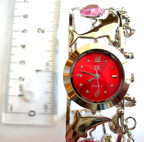 Fashion beaded bangle watch in rounded clock face design with carved-out pattern and jiggle bell decor on band