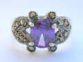 Sterling silver ring with multi marcasite embedded in 2 heart shape aside holding oval purple cz stone in center