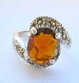 Central open design sterling silver ring with a oval orange cz stone embedded in middle and marcasite stones on top and bottom end