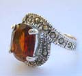Central open design sterling silver ring with a oval orange cz stone embedded in middle and marcasite stones on top and bottom end