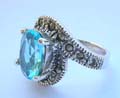 Central open design sterling silver ring with a oval light blue cz stone embedded in middle and marcasites on top and bottom end 