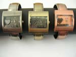 Bronze, copper, shiny grey cuff watch with rectangular shape and heart pattern inlaid on clock face