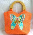Orange canvas fabric with sequins wooden handle hand bag motif butterfly feature in sparkle chips and thread work design with zipper closure and inner zipper pocket 
