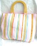 Fabric pink wooden handle hand bag with orange, green, blue and nature color line section and yellow sparkle chips thread work design, also inside zipper pocket, cell phone pocket and zipper closure 