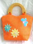 Orange canvas fabric with sequins hand bag motif green and yellow flowers with butterfly on right hand side in sparkle chips and thread work, also wooden handle design 