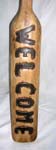 Angry skull head on tan colored wooden post with WELCOME sign etched in